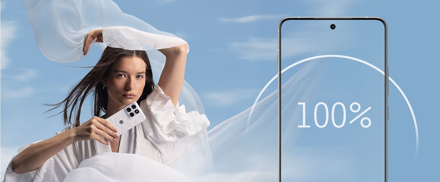 Kobieta w białej sukni trzymająca smartfon motorola edge 70 na tle błękitnego nieba